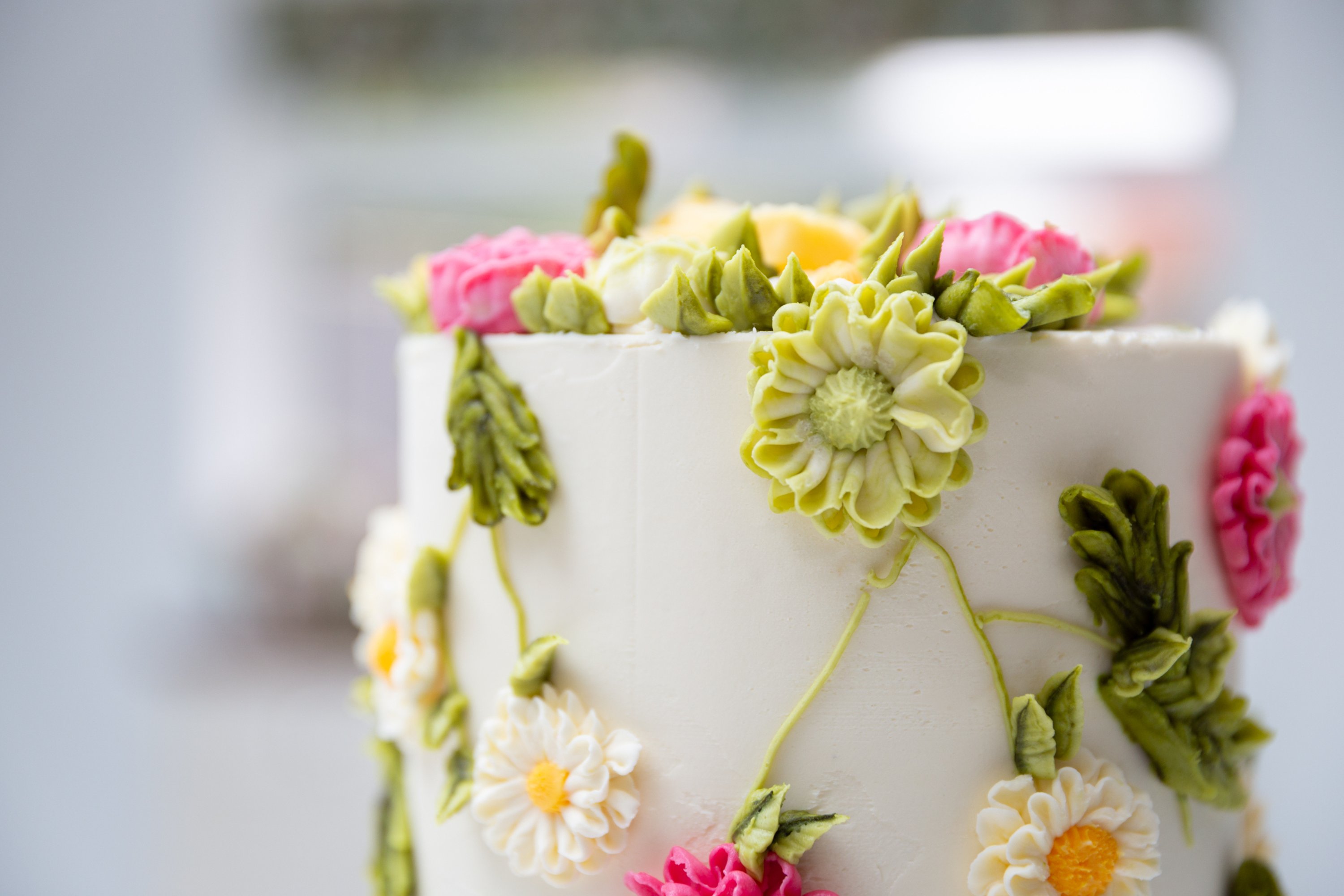 A single layer white wedding cake decorated with green, pink and white icing flowers