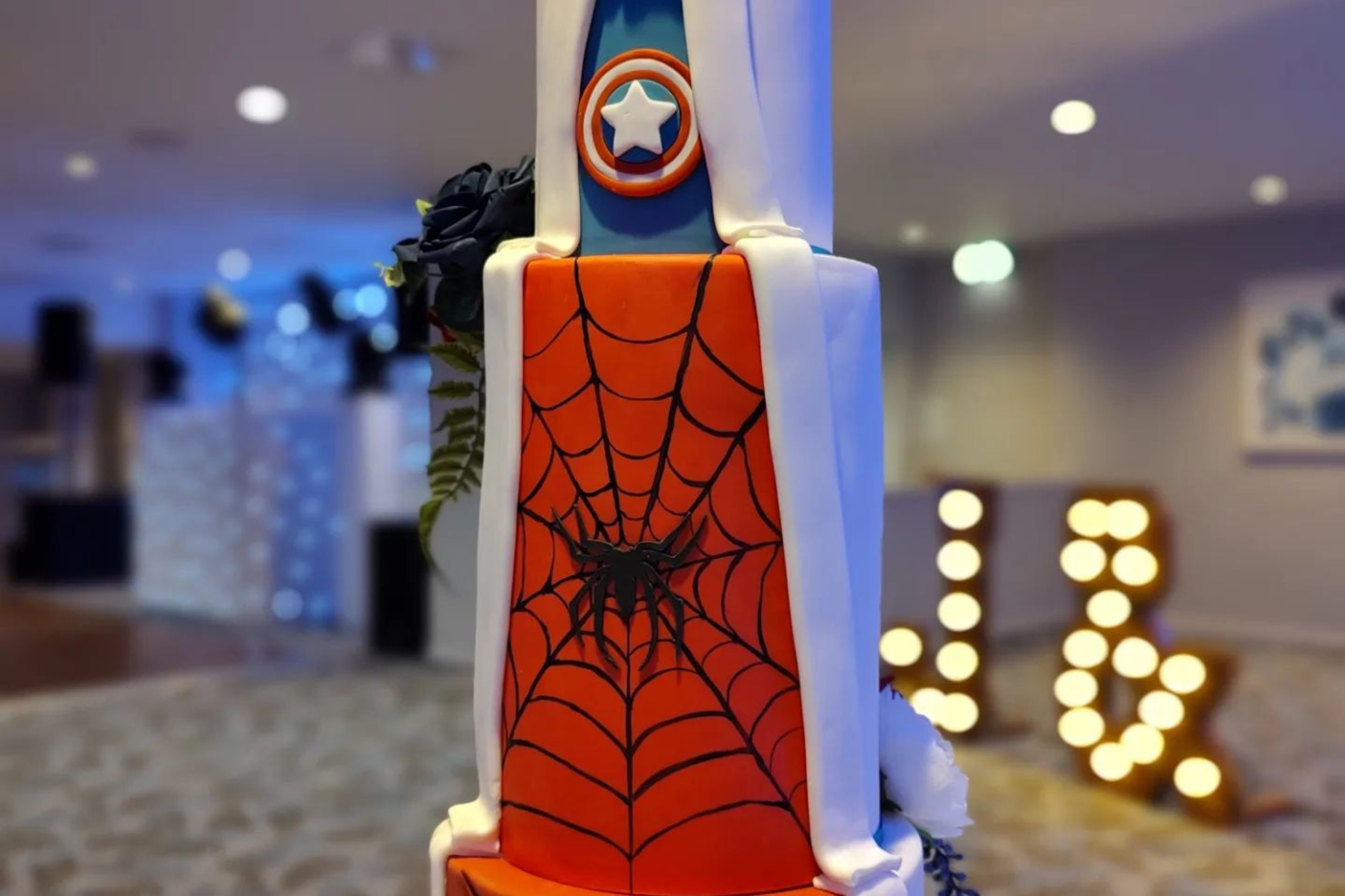 A three tiered Spiderman wedding cake with red, white and blue superhero decor
