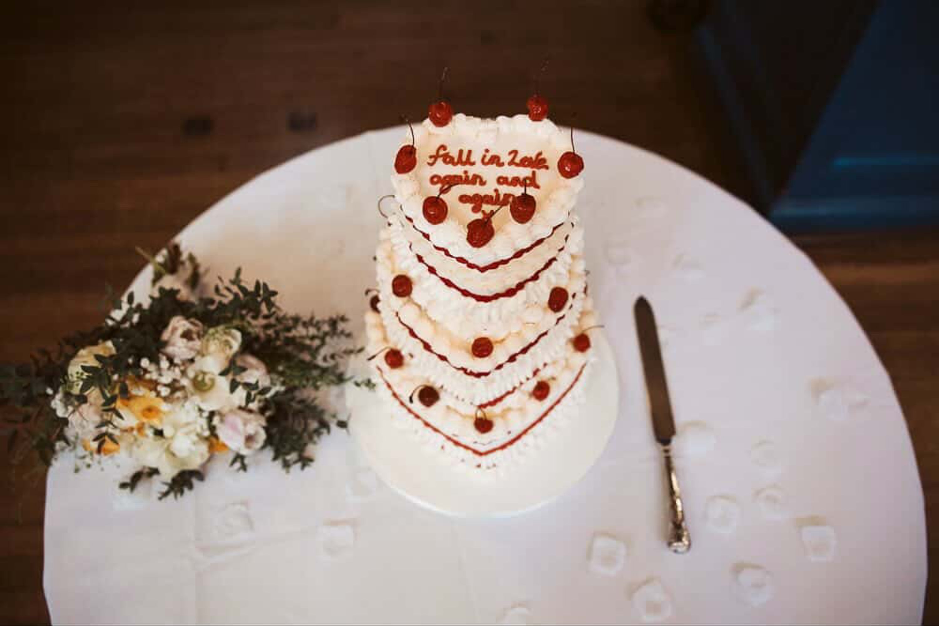 A three-tier retro heart shaped white cake topped with red icing and red cherries