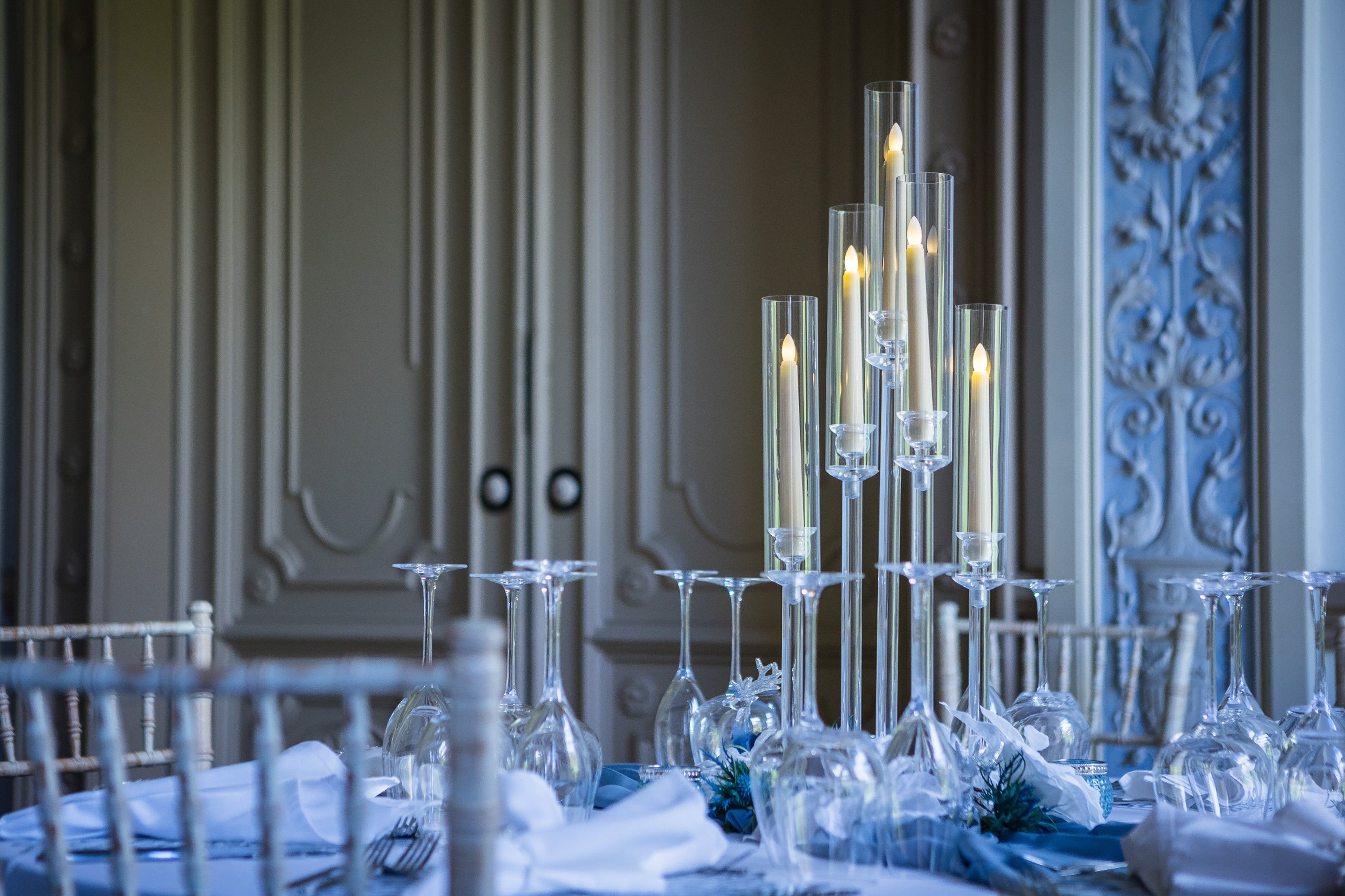 long tapered white candles on a white round table dressed for a wedding
