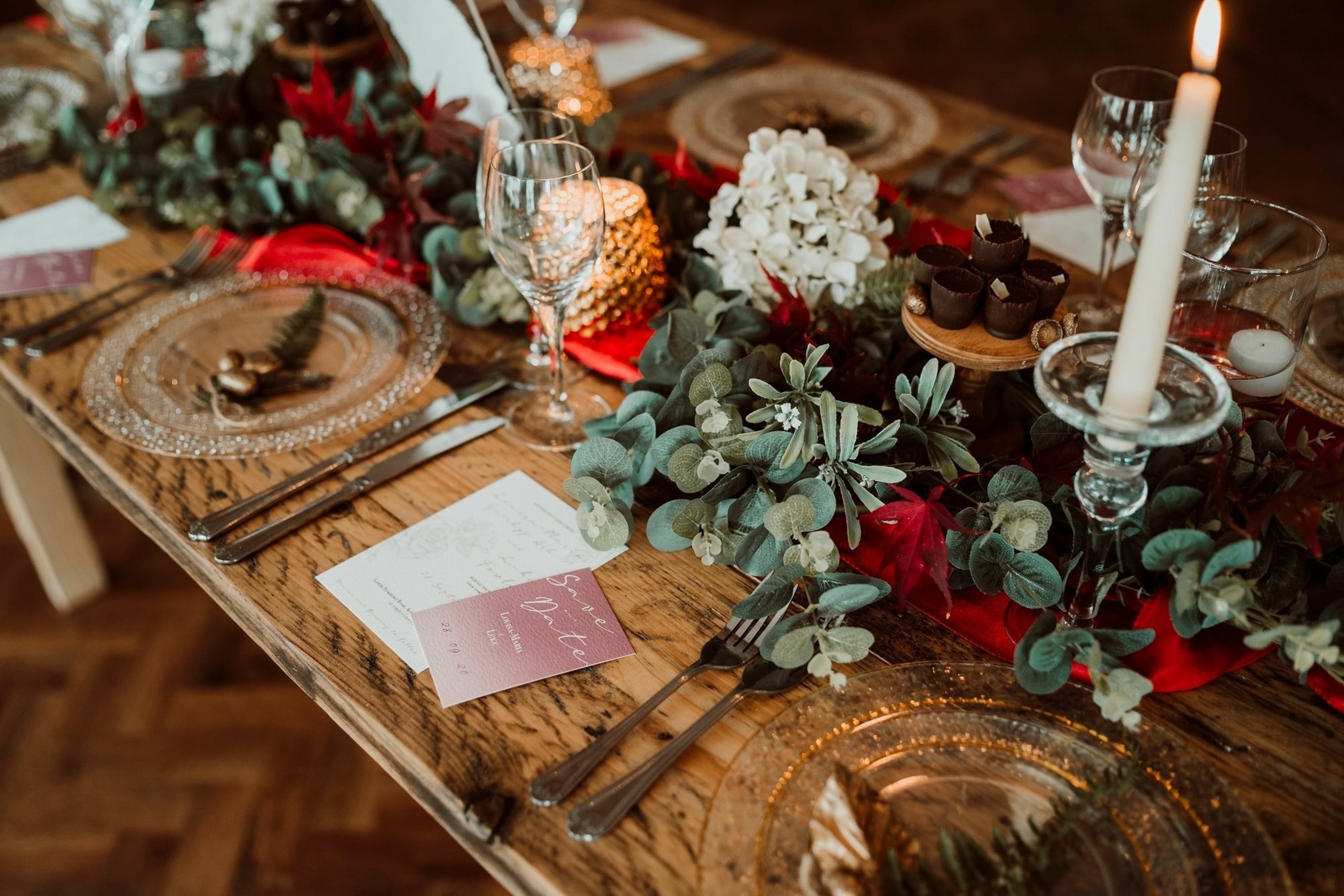 wintery table decor at a wedding displaying dried eucalyptus around glassware, tapered candles and tealights