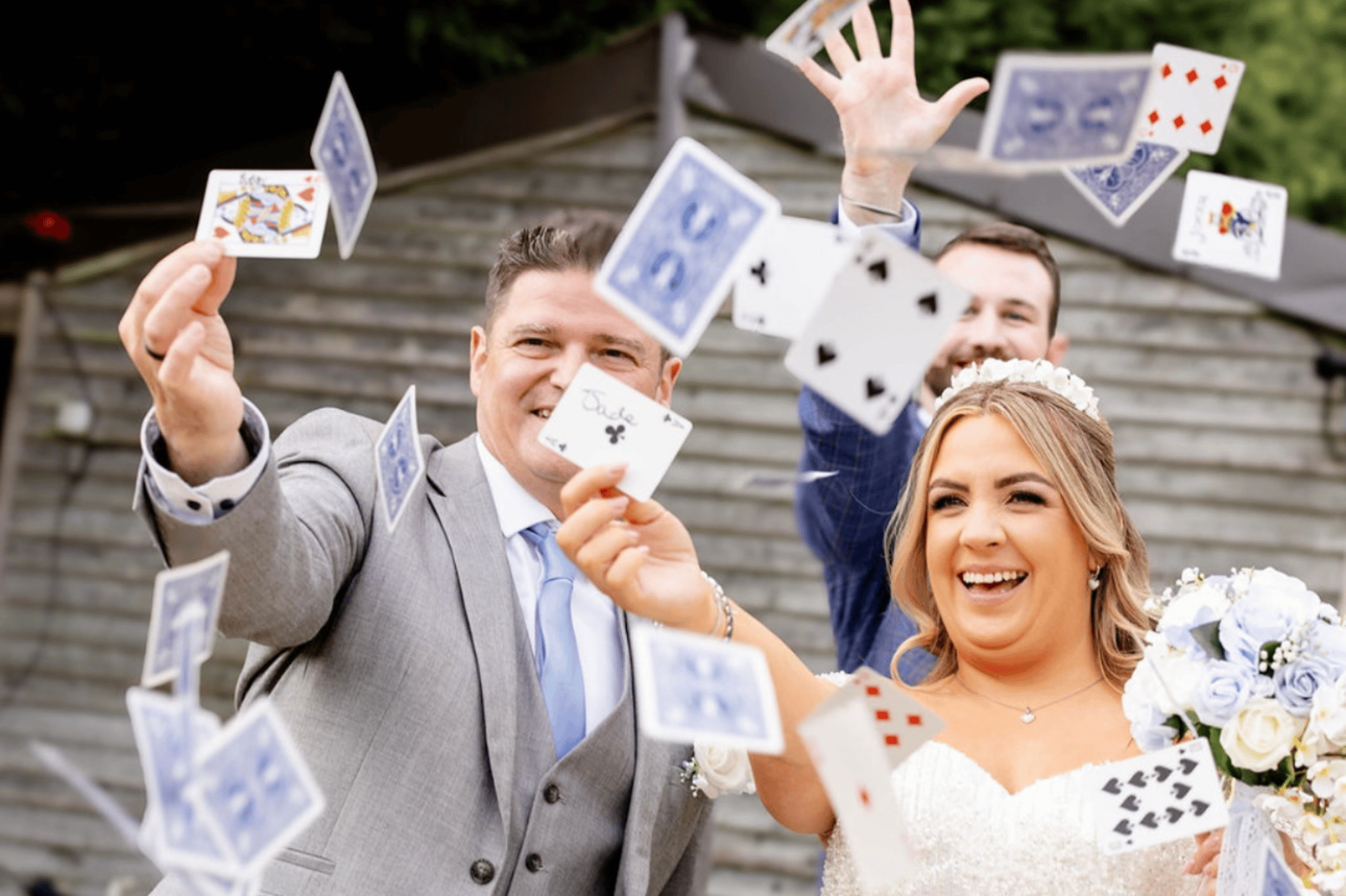 Bride and groom with a magician throwing playing cards