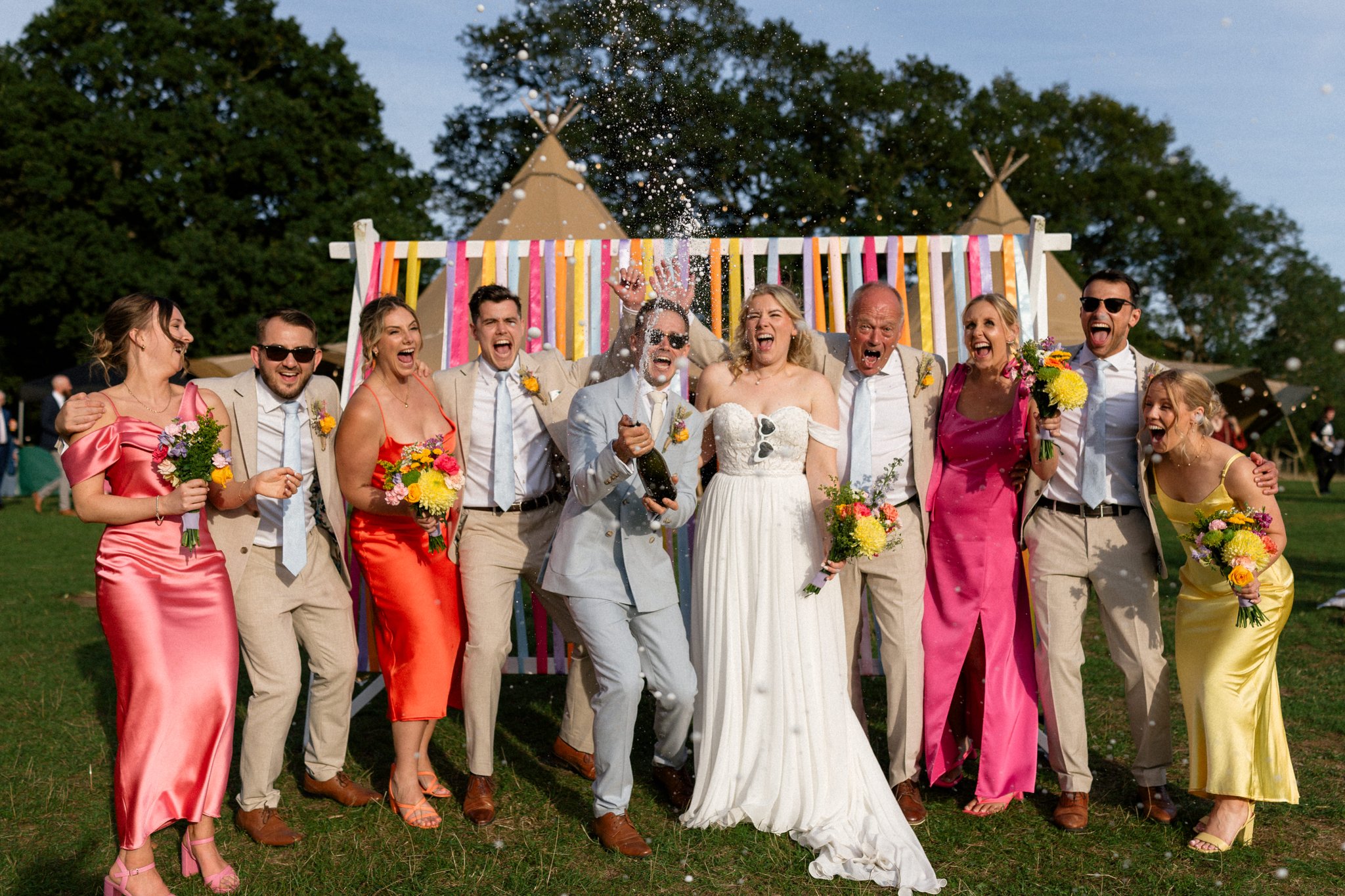 A wedding party laughing and spraying champagne