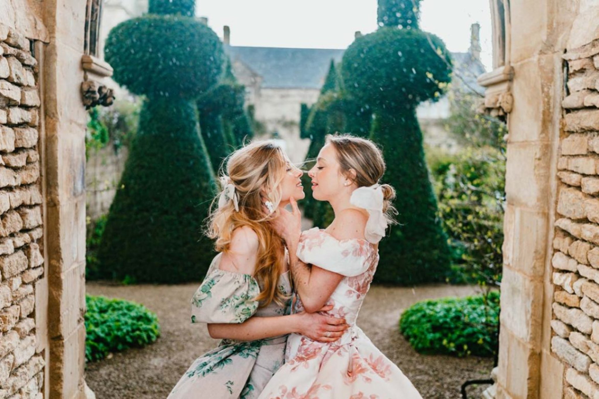 Two brides in ball gowns embracing