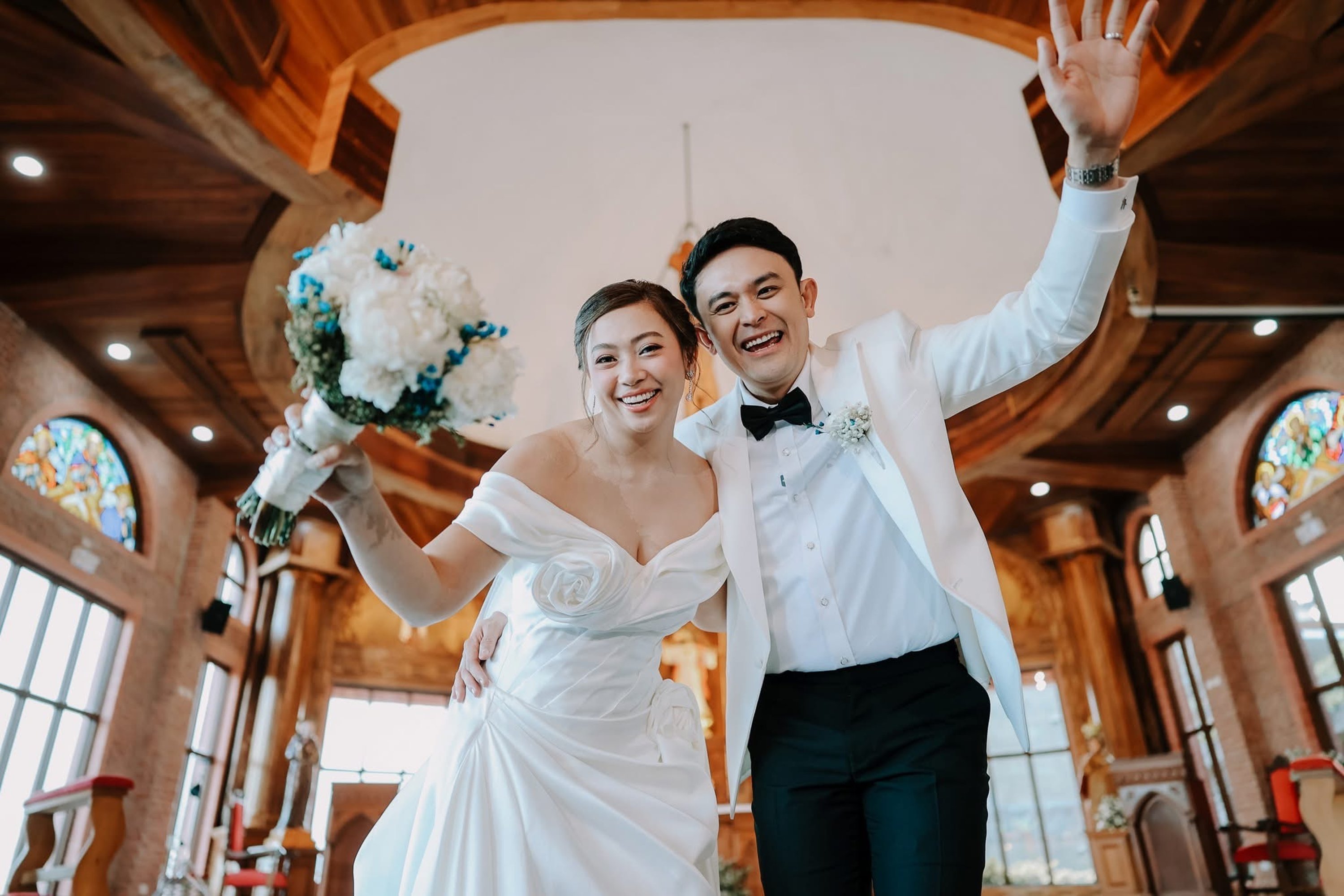 a bride and groom looking down at a lower angle lens, laughing and embracing in a grand hall wedding venue