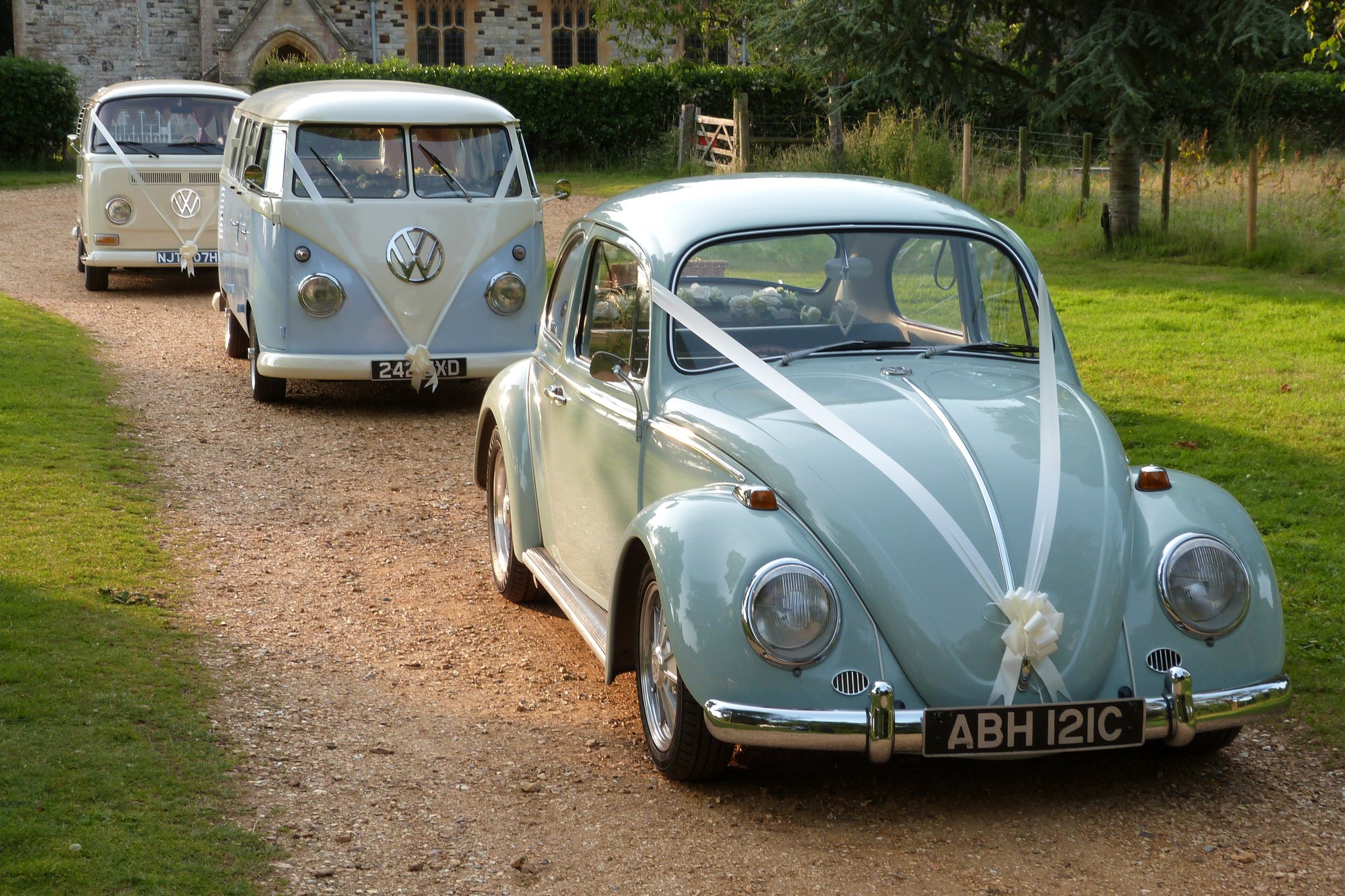 Line of vintage wedding cars including two VW campervans and one pale blue vintage Beetle
