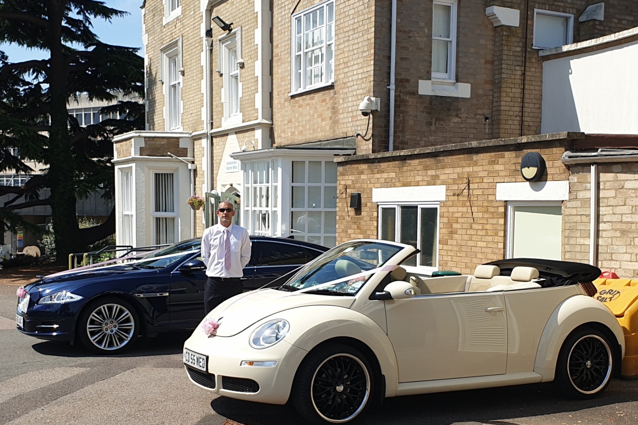 Chauffeur standing next to two wedding cars