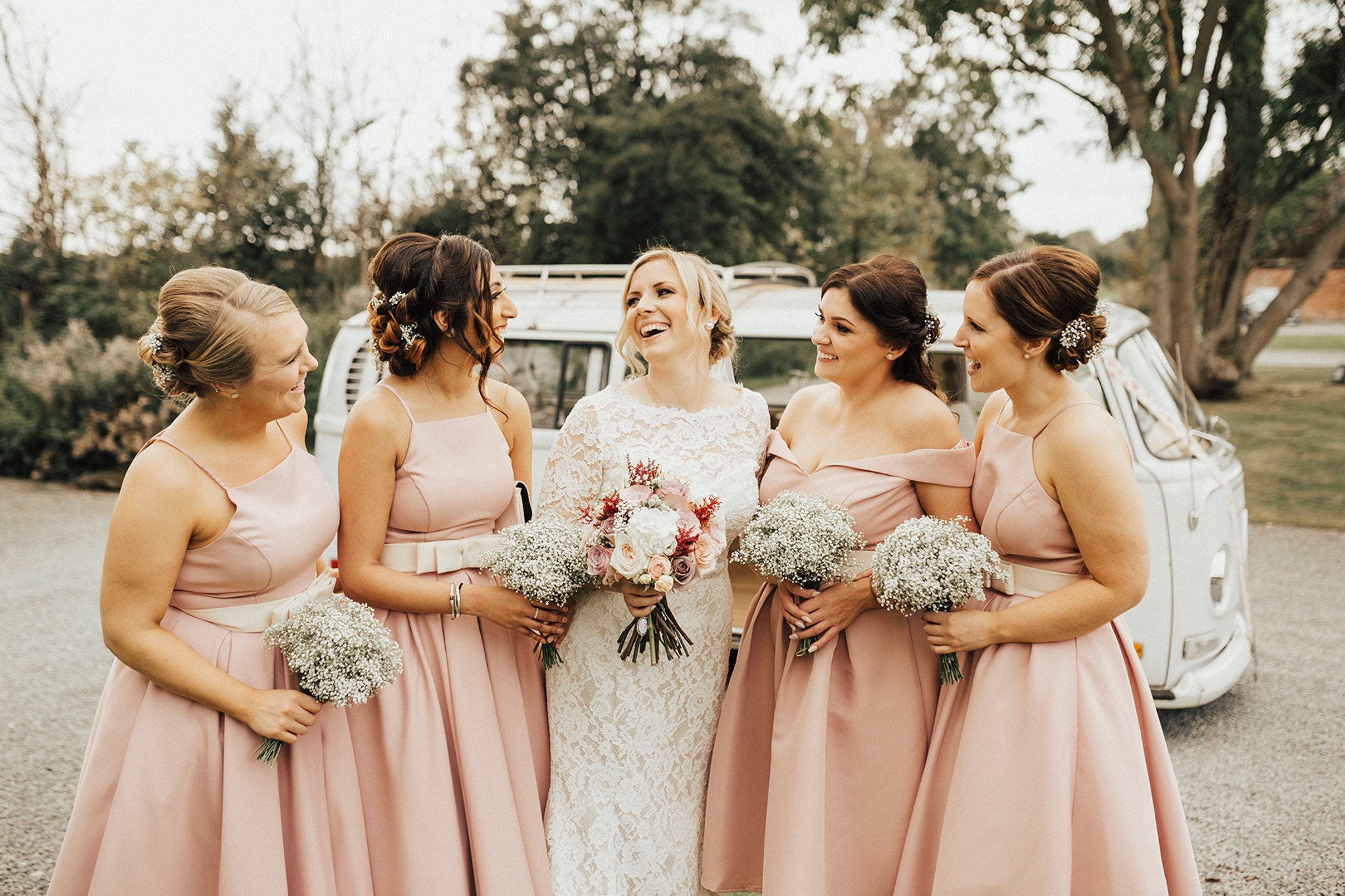 A bride and bridesmaids posing with a vintage camper van in the background