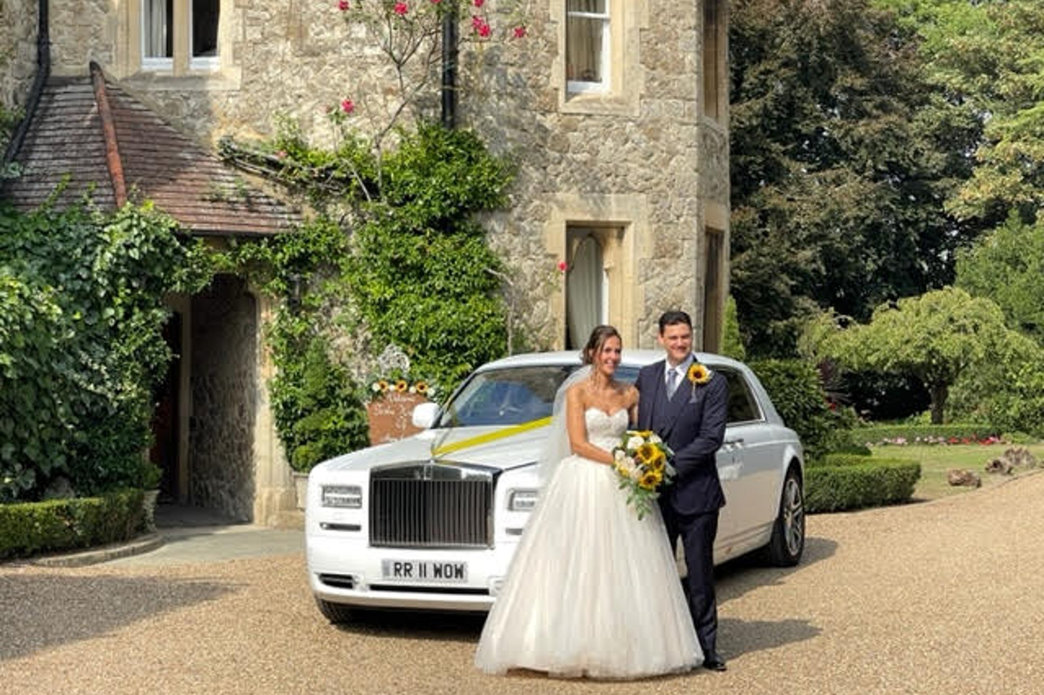 Bride and groom posing with a modern Rolls Royce wedding car