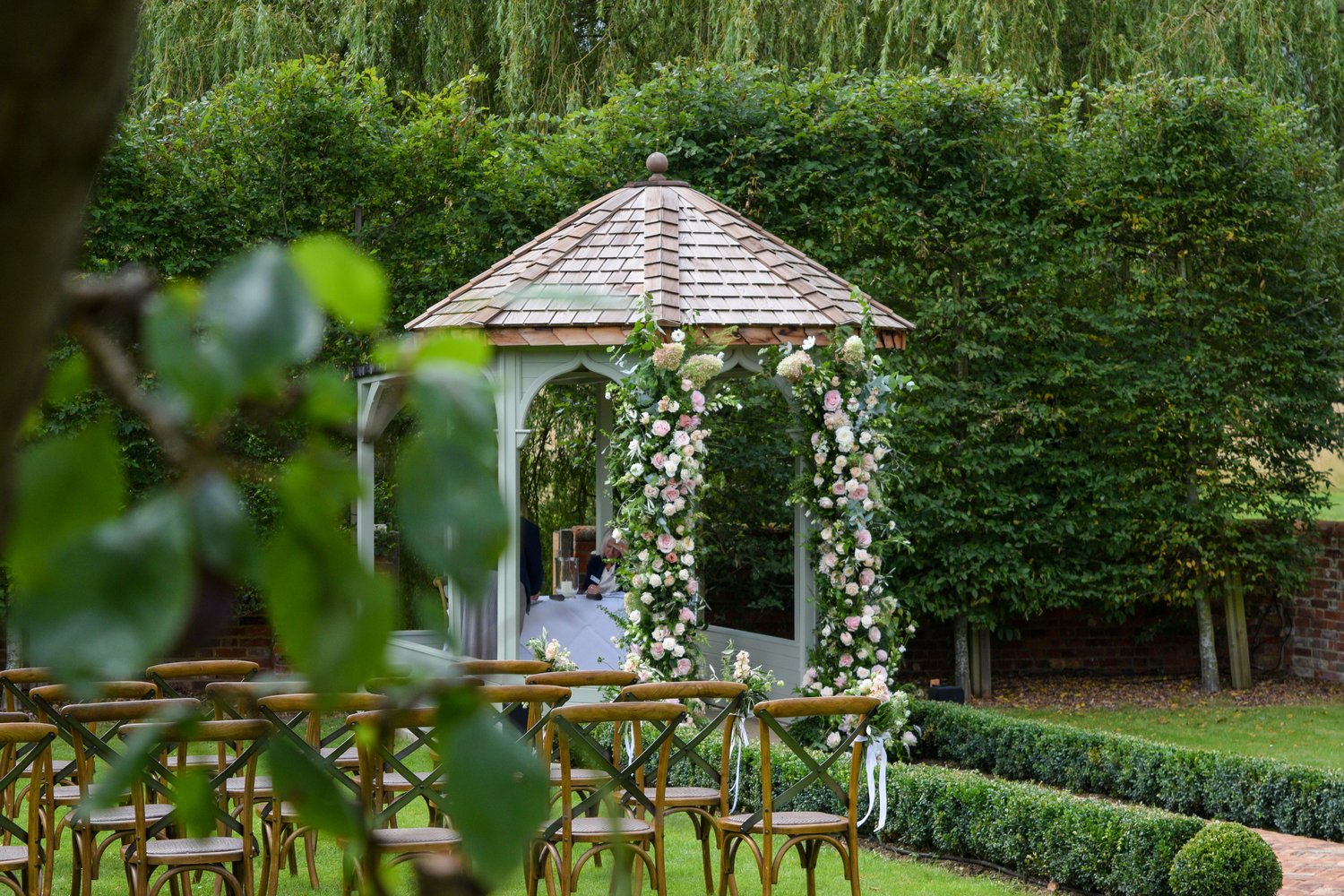 garden set up for a wedding ceremony with chairs and floral decorations on a pavilion