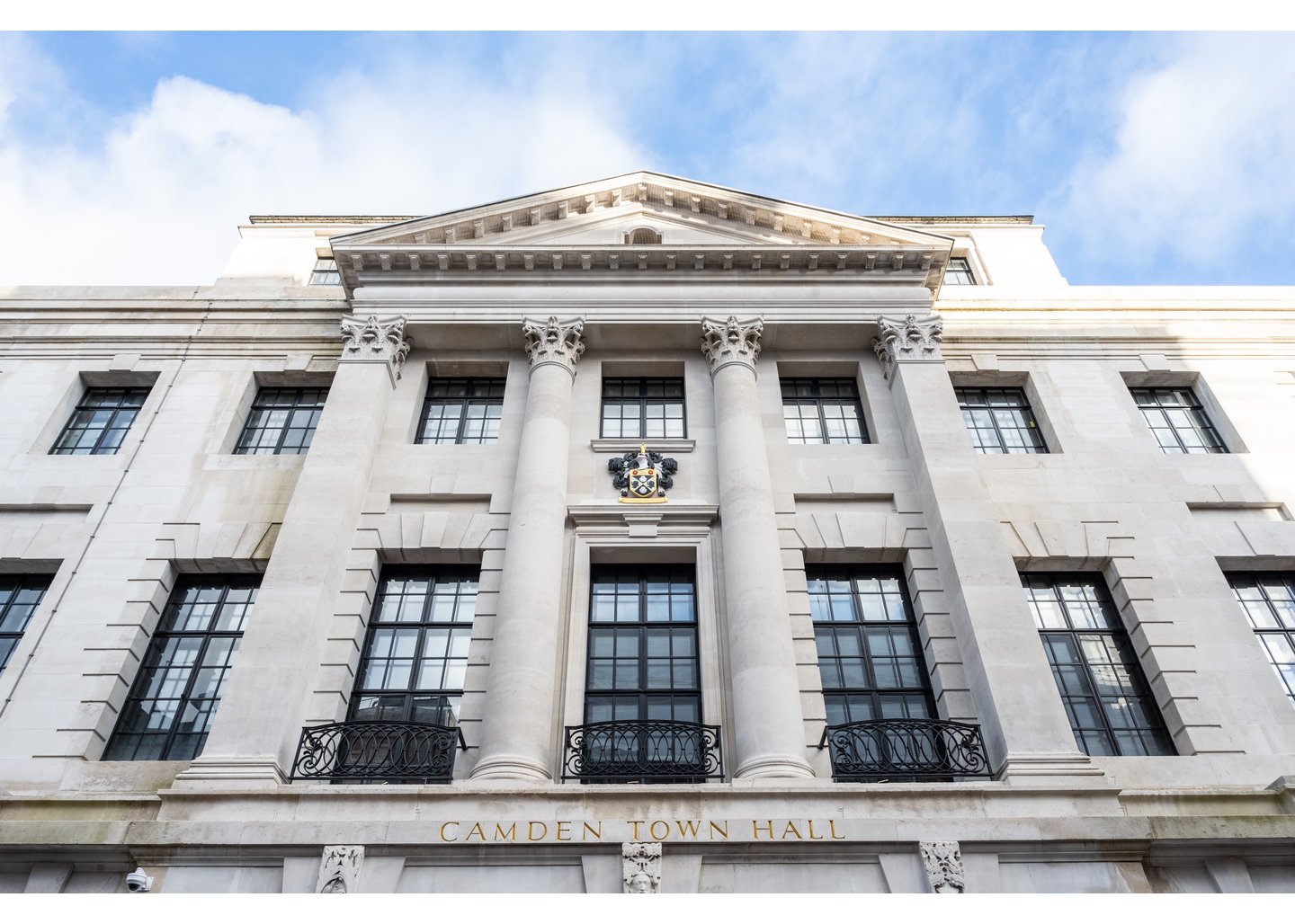 Outdoor view of Camden Town Hall, a large white building with pillars and long black windows