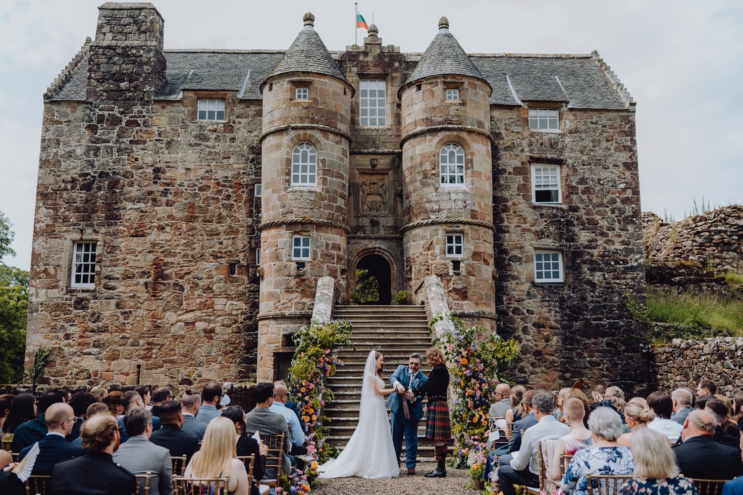 a couple having their wedding ceremony outside the castle