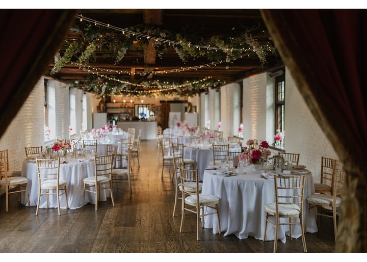 Inside a rustic wedding venue set up for the wedding breakfast