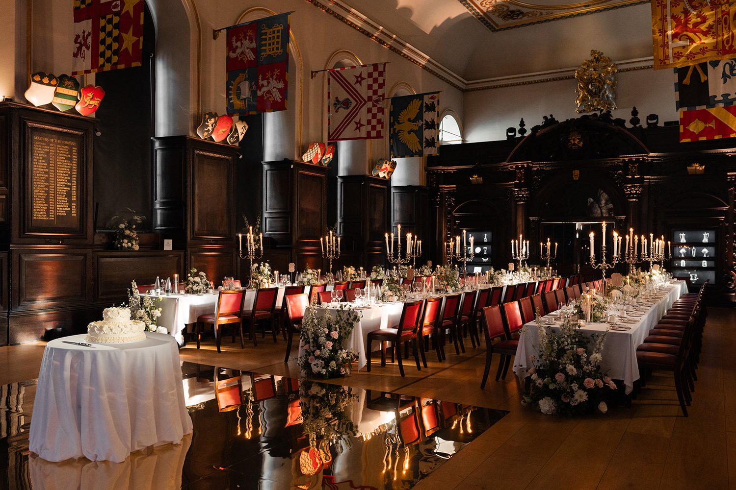 wedding breakfast set up inside with flags onthe walls and floral decorations with red chairs