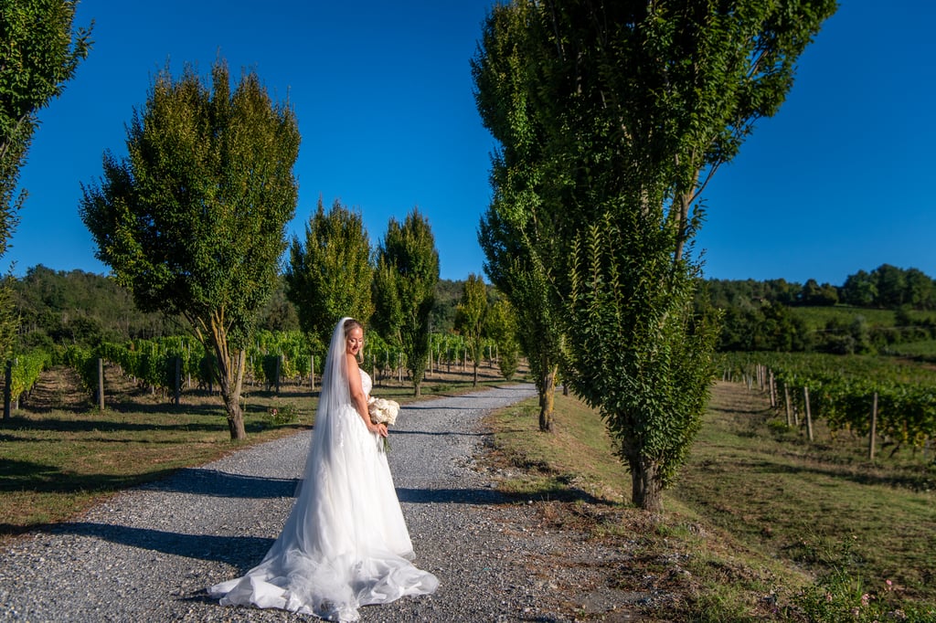 A bride being photographed in an avenue of trees by a wedding content creator